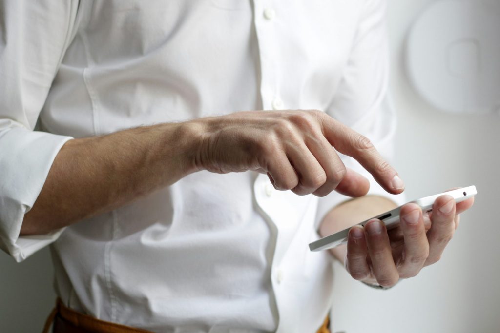 Persona con un teléfono inteligente Android blanco y camisa blanca